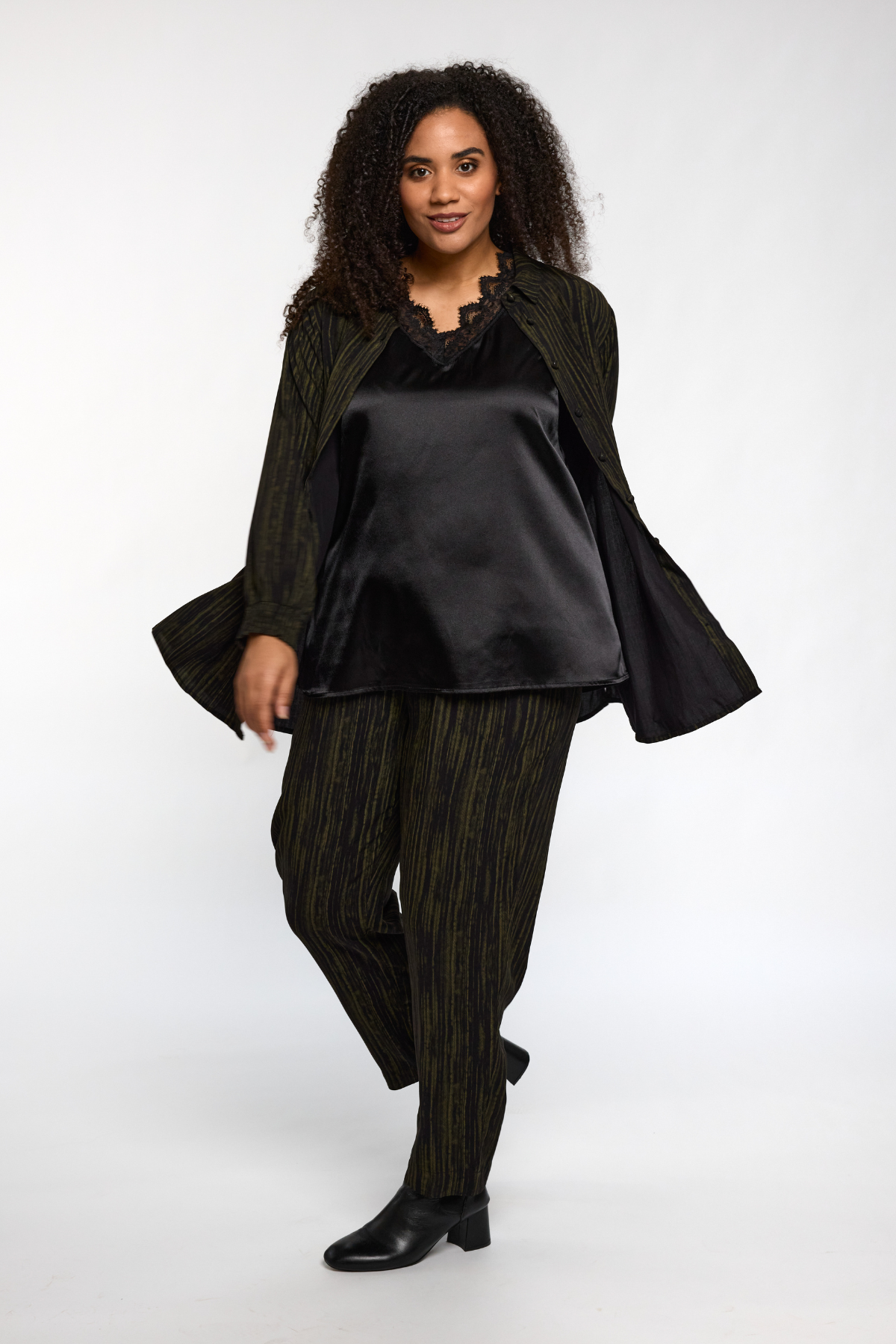 Model iført sort Ingrid top fra STUDIO stylet med mønstret skjorte og bukser.