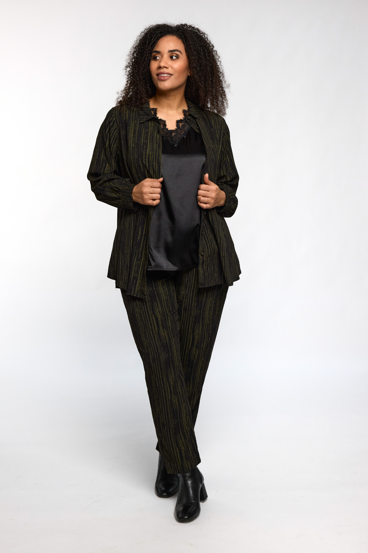 Model viser Ingrid top i sort fra STUDIO under åben skjorte – elegant look.