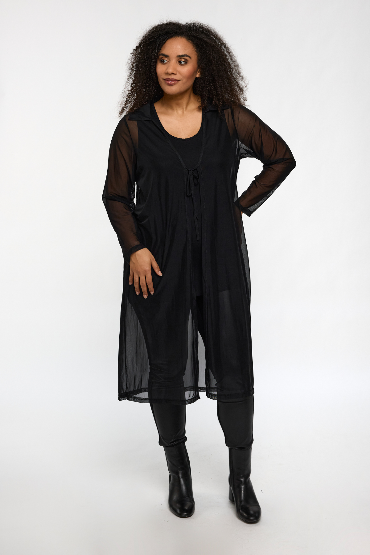 Model iført Nana Cardigan Sort fra STUDIO – langt åbent design i gennemsigtigt mesh med bindebånd.